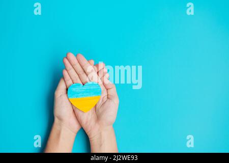 Soutien à l'Ukraine dans la guerre avec la Russie, mains tenant symbole de coeur avec le drapeau de l'Ukraine. Priez, pas de guerre, arrêtez la guerre et tenez-vous avec l'Ukraine Banque D'Images