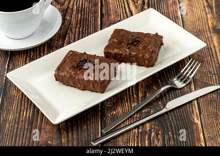 Gâteau au raisin recouvert de chocolat sur table en bois avec café filtre Banque D'Images