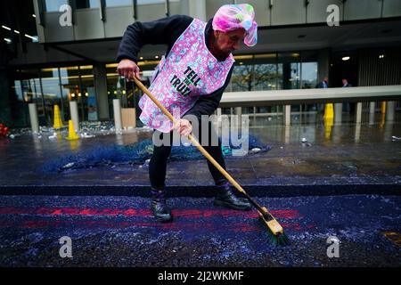 Un activiste de la rébellion des océans balaye le pétrole factice lors d'une manifestation en dehors de l'Organisation maritime internationale (OMI) dans le centre de Londres. Date de la photo: Lundi 4 avril 2022. Banque D'Images