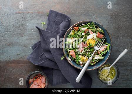 Salade de pissenlits avec œufs et bacon sur fond gris Banque D'Images