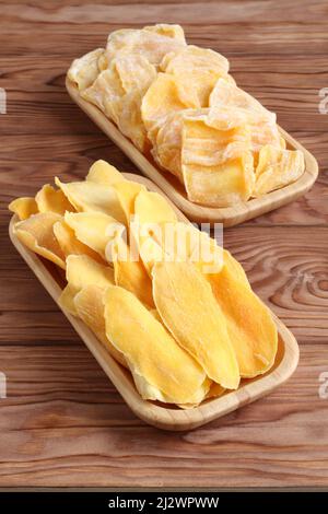 Morceaux séchés de mangue et de jackfruit sur une plaque de bambou sur une table en bois. Macro. Gros plan. Banque D'Images