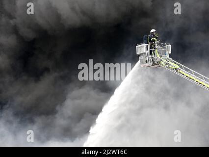 Mulheim, Allemagne. 04 avril 2022, Rhénanie-du-Nord-Westphalie, Mülheim an der Ruhr : le service des incendies éteint l'incendie dans un entrepôt. Un carrousel pour enfants sur une remorque de camion avait pris feu pour des raisons encore inconnues. En raison de la forte émission de fumée, des messages d'avertissement ont été publiés via l'application d'avertissement Nina. Photo: Roland Weihrauch/dpa crédit: dpa Picture Alliance/Alay Live News Banque D'Images