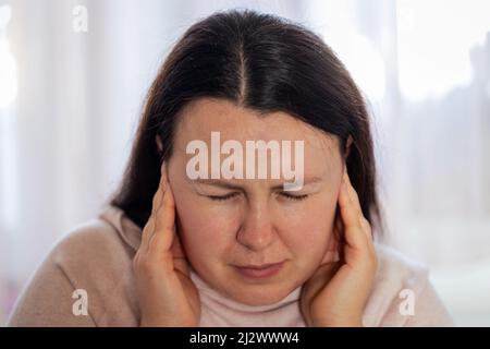 La jeune femme a un mal de tête de stress de migraine ou acouphène - sifflement de bruit dans ses oreilles. Banque D'Images