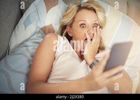 Qu'est-ce que je viens de lire. Photo d'une femme mûre qui a l'air surprise en lisant un message texte à la maison. Banque D'Images