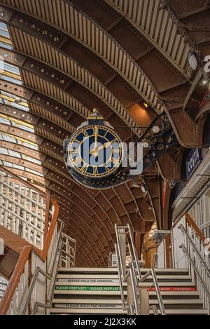 Une horloge de la gare très ornée est suspendue sous une voûte historique. Un vol de marches mène vers le haut et un café est d'un côté. Banque D'Images