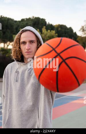 jeune homme tenant un ballon d'une main, se concentrer sur l'homme, concept de sport urbain dans la rue, espace de copie pour le texte Banque D'Images