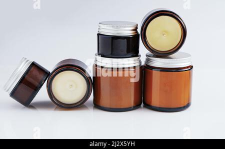 Un ensemble de différentes bougies aromatiques dans des pots en verre sur fond blanc. Bougie parfumée faite à la main. Bougies de soja, de cire et de paraffine. Banque D'Images