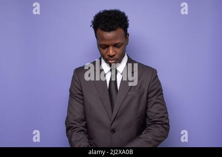 triste homme d'affaires africain fatigué ou épuisé regarder vers le bas. Prise de vue en studio. Banque D'Images