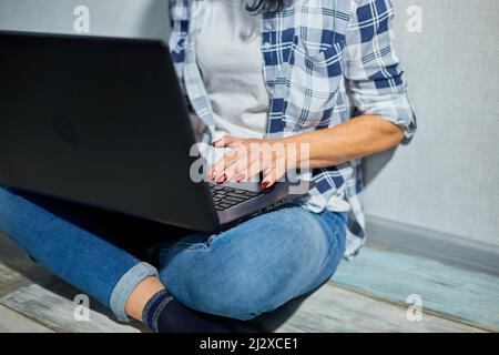 Une femme mûre et méconnaissable bavarde en ligne sur un réseau social en dactylographiant sur un clavier d'ordinateur portable, en travaillant, en écrivant des e-mails, femme senior freelance Banque D'Images