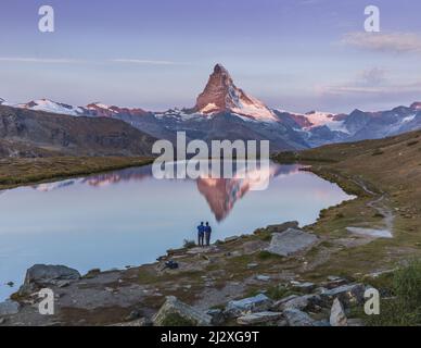 Couple de photographie bénéficiant d'une vue spectaculaire au lever du soleil depuis le lac Stellisee sur le mont Cervin près de Zermatt, Wallis, Suisse Banque D'Images