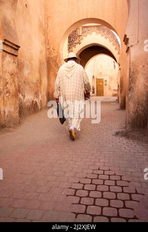Des hommes locaux vêtus de robe traditionnelle djellaba marchant dans la rue dans la vieille médina, Marrakech, Maroc Banque D'Images