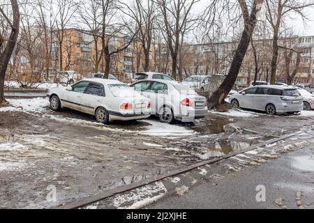 Russie, Vladivostok, 21 mars 2022. Voitures dans un parking sale après la neige. Les zones pauvres de la ville et les problèmes d'infrastructure. Transport et véhicules. Banque D'Images