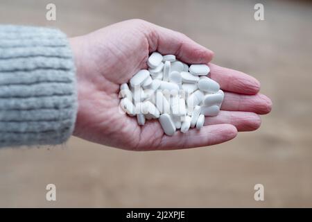 Une femme d'âge moyen tenant une grande poignée de comprimés de paracétamol blanc. Les comprimés sont non emballés, non marqué générique paracétamol analgésiques Banque D'Images