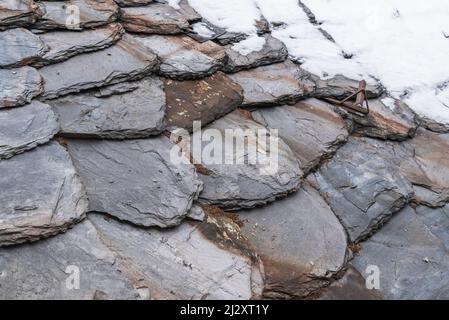 Vieux tuiles de toit gris, partiellement couvert de neige, fond. Banque D'Images