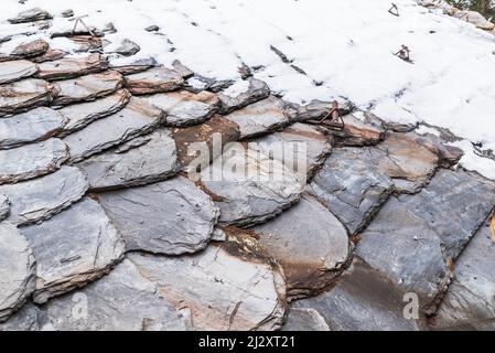 Vieux tuiles de toit gris, partiellement couvert de neige, fond. Banque D'Images