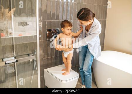 Mère se penchait sur son bébé garçon dans les toilettes Banque D'Images