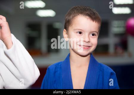 École de Judo pour enfants. Un petit garçon dans un kimano sourit à l'entraînement. Banque D'Images