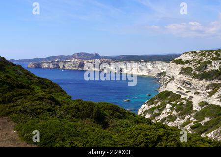 Bonifacio, Corse-du-Sud: Vue d'ensemble de la côte et des falaises de calcaire blanc du chemin côtier. En arrière-plan, la citadelle et la vieille ville o Banque D'Images