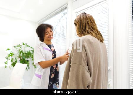 Belle jeune femme mixte race médecin avec patiente enceinte devant le participant, porte-jarre de pilule et ordonnance écrite sur la forme. Médecine et ph Banque D'Images