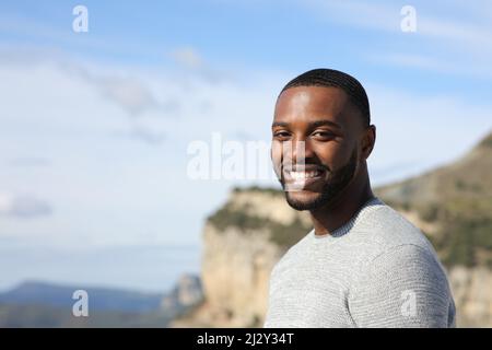 Portrait d'un bel homme heureux avec une peau noire regardant l'appareil photo dans la nature Banque D'Images