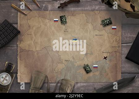 Carte de l'invasion russe de l'Ukraine avec du matériel militaire sur la table. Vue de dessus, composition du concept de pose à plat Banque D'Images