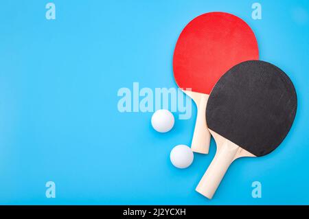 Leçon de ping-pong et gagnant défi de compétition concept avec tennis de table rouge et noir ou ping-pong paddle isolé sur fond bleu avec copie sp Banque D'Images