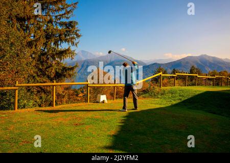 Golfeur Tearing off avec son chauffeur sur le terrain de golf Menaggio avec vue sur la montagne en automne dans Lombardie, Italie. Banque D'Images