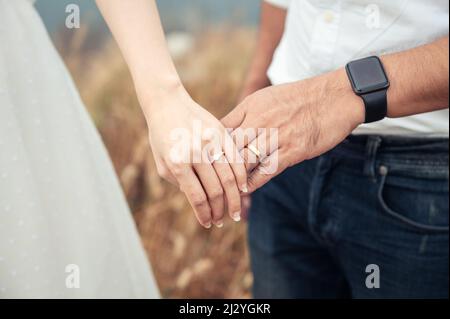 La mariée et le marié debout en gros plan tiennent les mains avec l'anneau de mariage dans la forêt avant le mariage. Robe de mariage, couple marié Banque D'Images