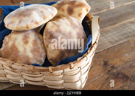 Panier en bois avec plusieurs morceaux de pain pita maison sur une table en bois. Copier l'espace. Banque D'Images