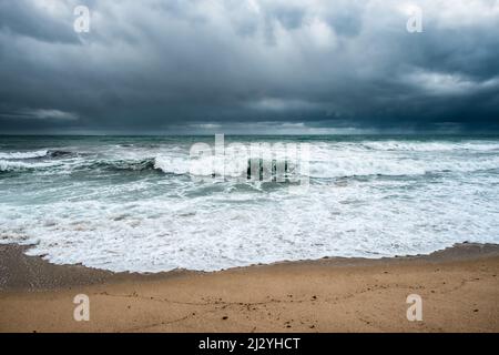 Les mers agitées se sont écraées sur la plage d'Algajola dans la région de Balagne en Corse avec des nuages sombres et de la pluie à l'horizon Banque D'Images
