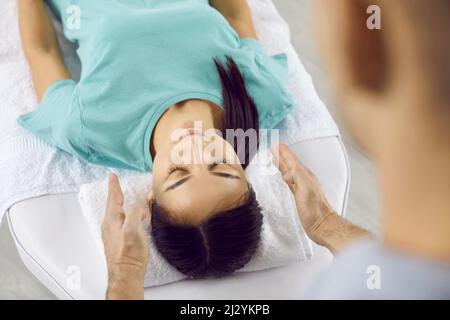 Jeune femme se détendant pendant la séance de thérapie holistique avec le spécialiste de guérison Reiki Banque D'Images