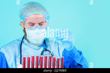 Médecin vérifiant les échantillons de sang en laboratoire. Homme chercheur en combinaison et masque de protection personnelle Banque D'Images