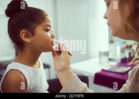 Shes une petite princesse. Photo d'un styliste appliquant du maquillage à une petite fille mignonne dans un dressing. Banque D'Images