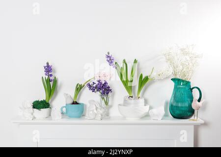 Jacinthe blanche dans un grand bol en porcelaine, figurines de lièvres et un oiseau, sont sur la cheminée contre le mur blanc. Mise en page. Concept de ressort Banque D'Images