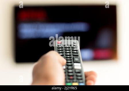 Télécommande de télévision à main mâle adulte avec écran anonyme à la télévision Banque D'Images