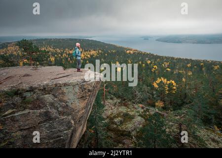 Femme sur la falaise de roche Predikvolent sur Getsvedjeberget avec une vue sur le paysage de Höga Kusten dans l'est de la Suède Banque D'Images