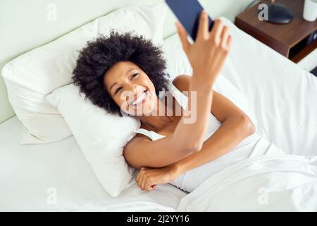 Je suis heureux d'accepter un autre jour, alors je prends un selfie. Photo courte d'une jeune femme attrayante prenant un selfie au lit à la maison. Banque D'Images