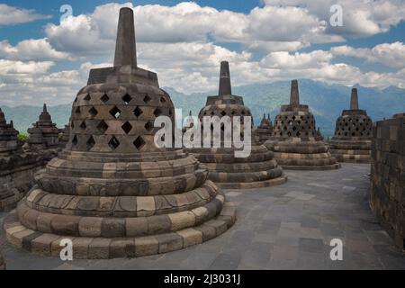 Borobudur, Java, Indonésie. Stupas sur le niveau supérieur du temple. Les trous en forme de diamant symbolisent les passions qui s'attardent pendant que les hommes s'élèvent à Nirvana. Banque D'Images