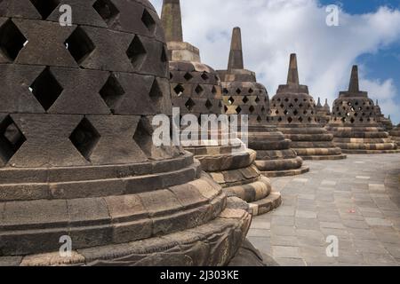 Borobudur, Java, Indonésie. Stupas sur le niveau supérieur du temple. Les trous en forme de diamant symbolisent les passions qui s'attardent pendant que les hommes s'élèvent à Nirvana. Banque D'Images