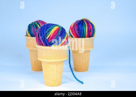 Billes de fils multicolores en cônes de crème glacée isolées sur fond bleu clair Banque D'Images