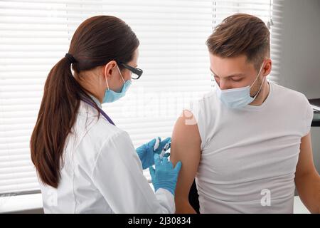 Le médecin tient une seringue avant de donner une injection à un patient dans un masque médical. Vaccin Covid-19 ou coronavirus. Vaccination de la population Banque D'Images