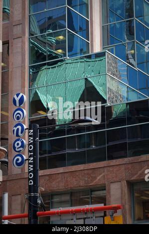 Toronto, Canada - 06 27 2016: Panneau de rue de fantaisie Yonge monté sur un poteau de feu de rue tourné devant un mur de bâtiment vitreux reflétant le toit vert Banque D'Images