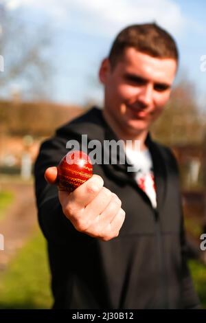 Recentrer le jeune ukrainien tenant un œuf rouge coloré sur fond de nature. Pâques, Ukraine. Œufs peints artisanaux. Pysanka ou krashanka. Hors foyer. Banque D'Images