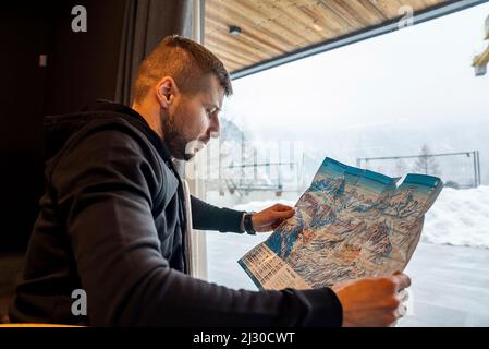 Jeune homme touriste explorant la carte de la station de ski et des pistes Banque D'Images