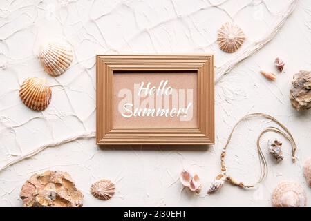 Texte Hello Summer dans cadre doré. Sur fond blanc avec étoiles de mer, coquillages, coquillages, collier. Filet de pêcheur sur fond blanc beige crème. Banque D'Images