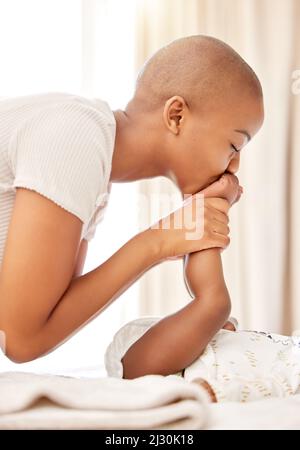 Maman vous adore beaucoup. Photo d'une mère embrassant les pieds de son bébé fille à la maison. Banque D'Images