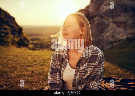 Jeune femme avec les yeux fermés appréciant la soirée d'été dans la nature. Banque D'Images