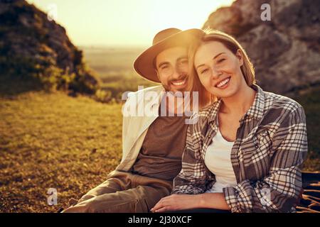 Portrait d'un jeune couple assis ensemble au coucher du soleil en montagne pendant les vacances d'été Banque D'Images
