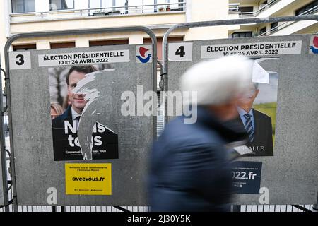 Un piéton passe sur un panneau d'affichage électoral une affiche de campagne officielle déchirée d'Emmanuel Macron. Affiches présidentielles sur leurs conseils électoraux. Illustration le 4 avril 2022 à Paris, France. Les électeurs français se rendront aux urnes le 10 avril 2022 pour le premier tour de l'élection présidentielle. Photo de Victor Joly/ABACAPRESS.COM Banque D'Images