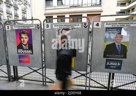 Un piéton passe devant des affiches déchirées de la campagne, sur un panneau d'affichage électoral (panneau). Affiches présidentielles sur leurs conseils électoraux. Illustration le 4 avril 2022 à Paris, France. Les électeurs français se rendront aux urnes le 10 avril 2022 pour le premier tour de l'élection présidentielle. Photo de Victor Joly/ABACAPRESS.COM Banque D'Images